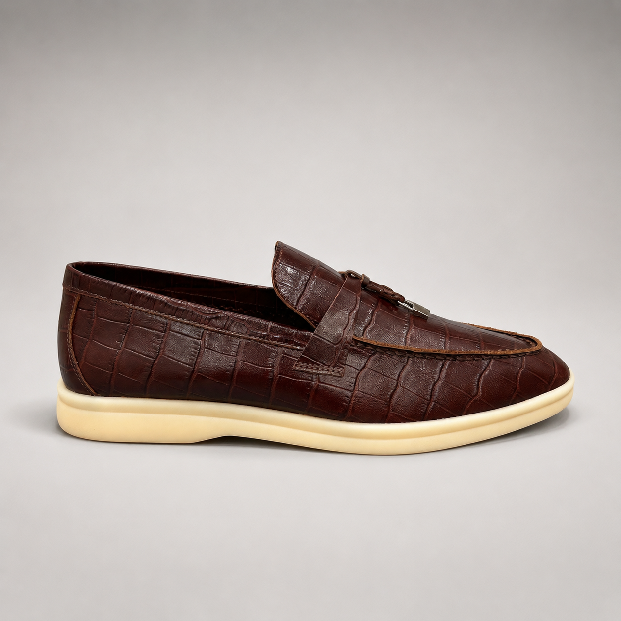 Brown loafer side profile showing a crocodile-pattern embossed upper and vamp strap