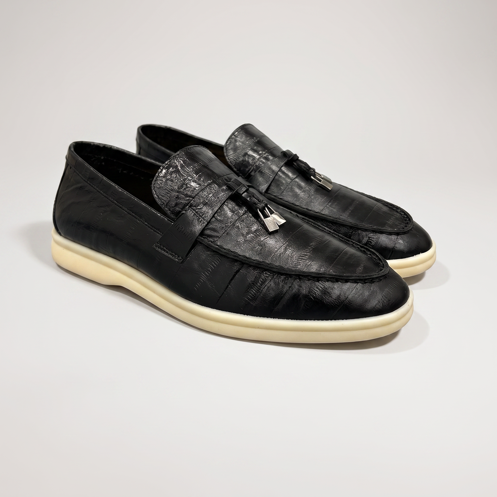 Black loafer pair three-quarter view showing an eel-pattern embossed vamp and tassel detail