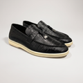 Black loafer pair three-quarter view showing an eel-pattern embossed vamp and tassel detail