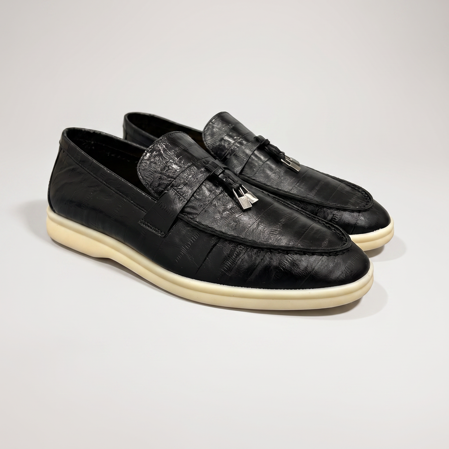 Black loafer pair three-quarter view showing an eel-pattern embossed vamp and tassel detail