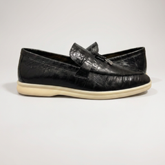 Black loafer inner side profile showing an eel-pattern embossed vamp and tassel detail