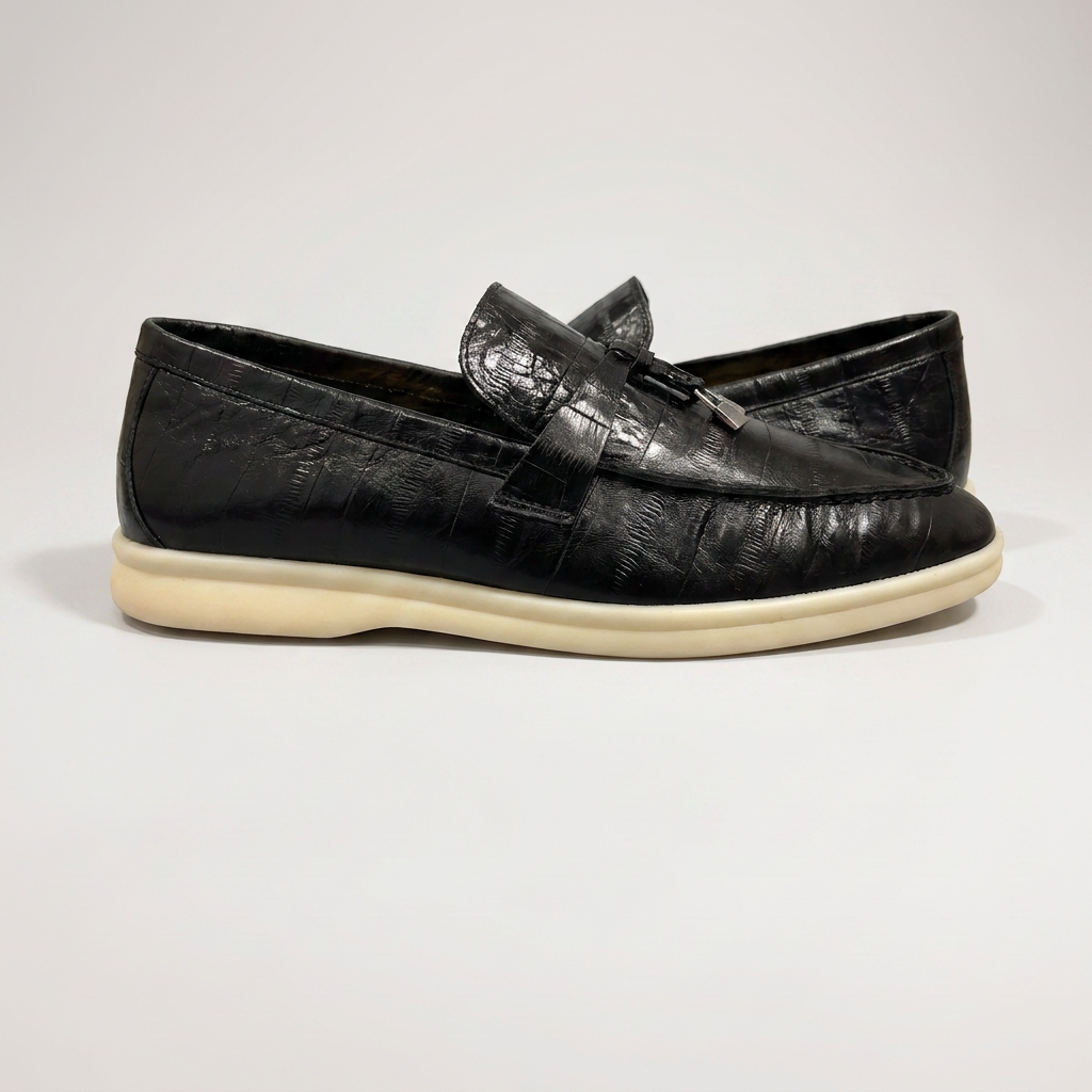 Black loafer inner side profile showing an eel-pattern embossed vamp and tassel detail