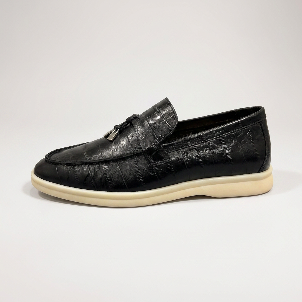 Black loafer outer side profile showing an eel-pattern embossed vamp and tassel detail
