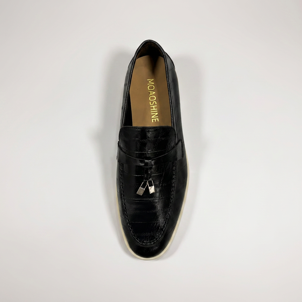 Black loafer top view showing an eel-pattern embossed vamp and tassel detail