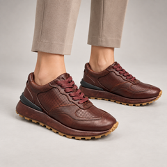Dark brown perforated leather platform sneakers worn on foot
