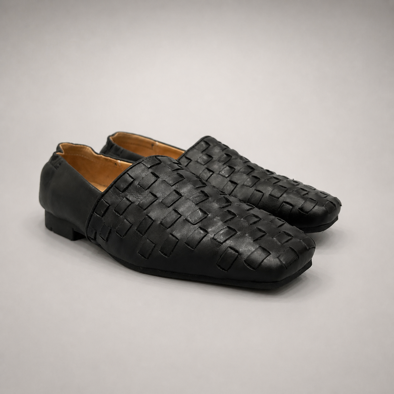 Black woven loafer pair three-quarter view showing a woven slip-on upper