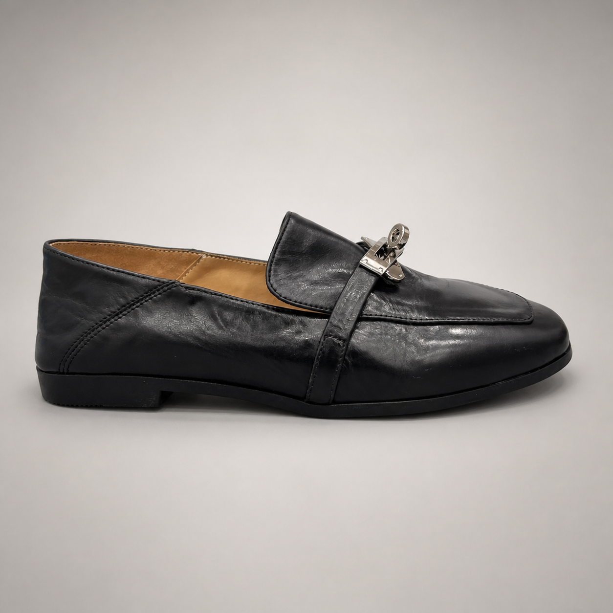 Black loafer side profile showing a metal accent across the vamp