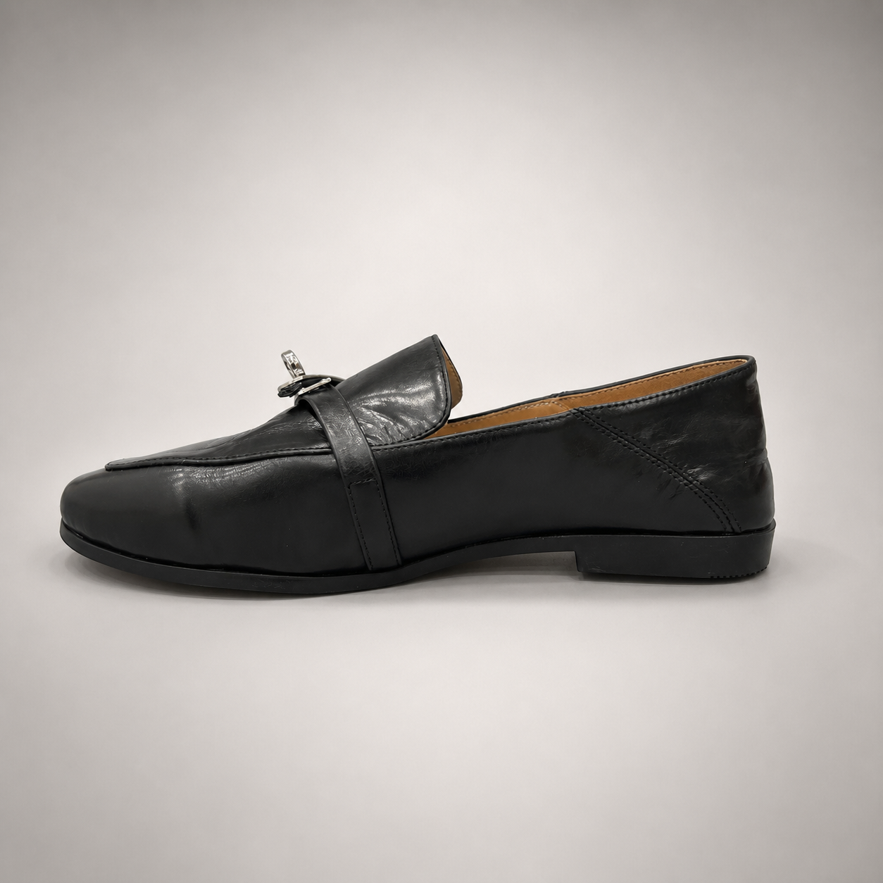 Black loafer opposite side profile showing a metal accent across the vamp
