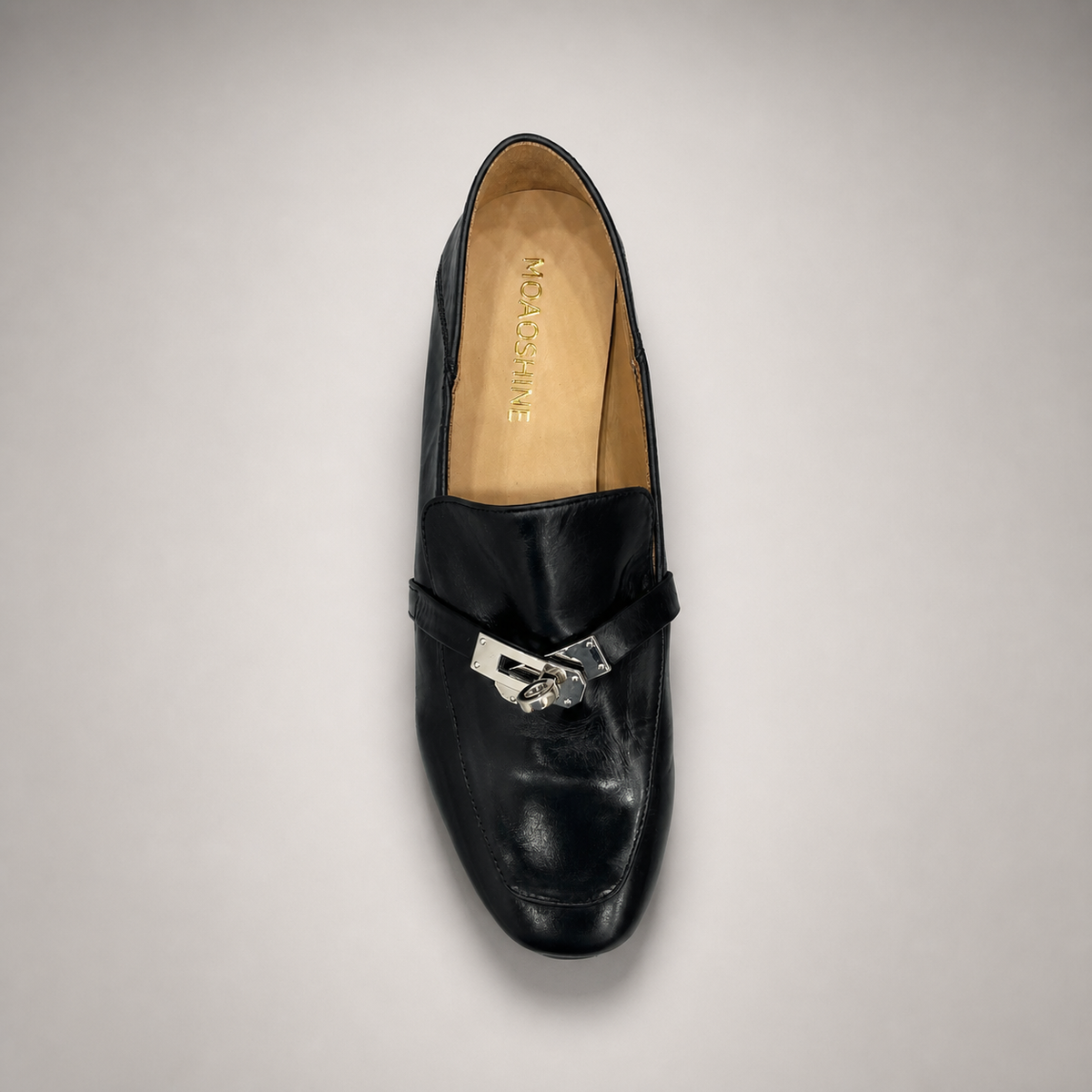 Black loafer top view showing a metal accent across the vamp