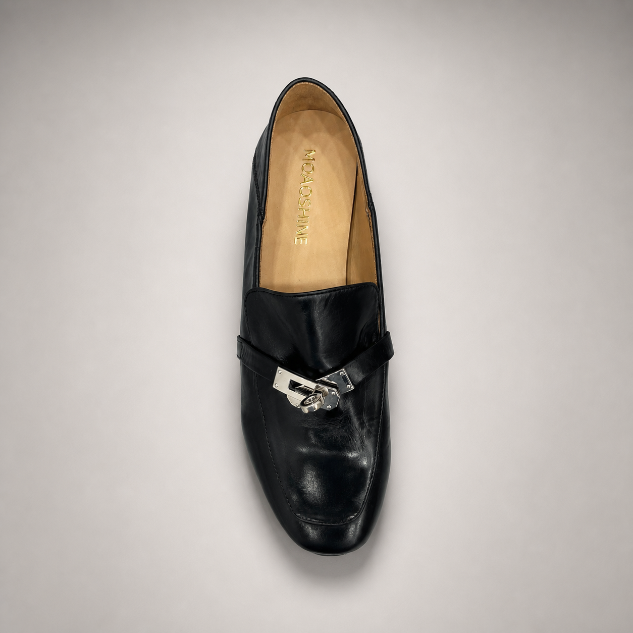 Black loafer top view showing a metal accent across the vamp