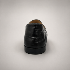 Black loafer rear view showing a metal accent across the vamp