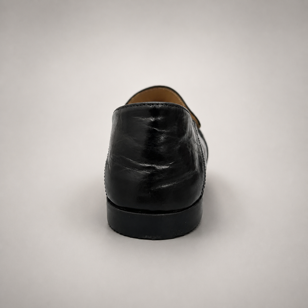 Black loafer rear view showing a metal accent across the vamp