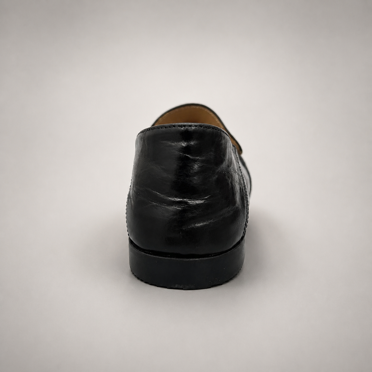 Black loafer rear view showing a metal accent across the vamp