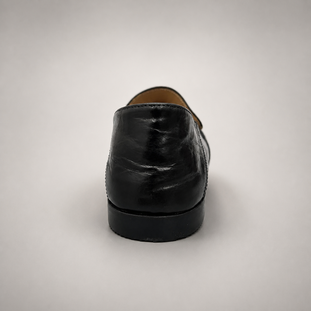 Black loafer rear view showing a metal accent across the vamp