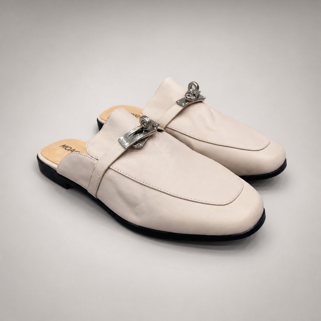 Ivory mule loafer pair three-quarter view showing an open-back mule construction and metal vamp accent