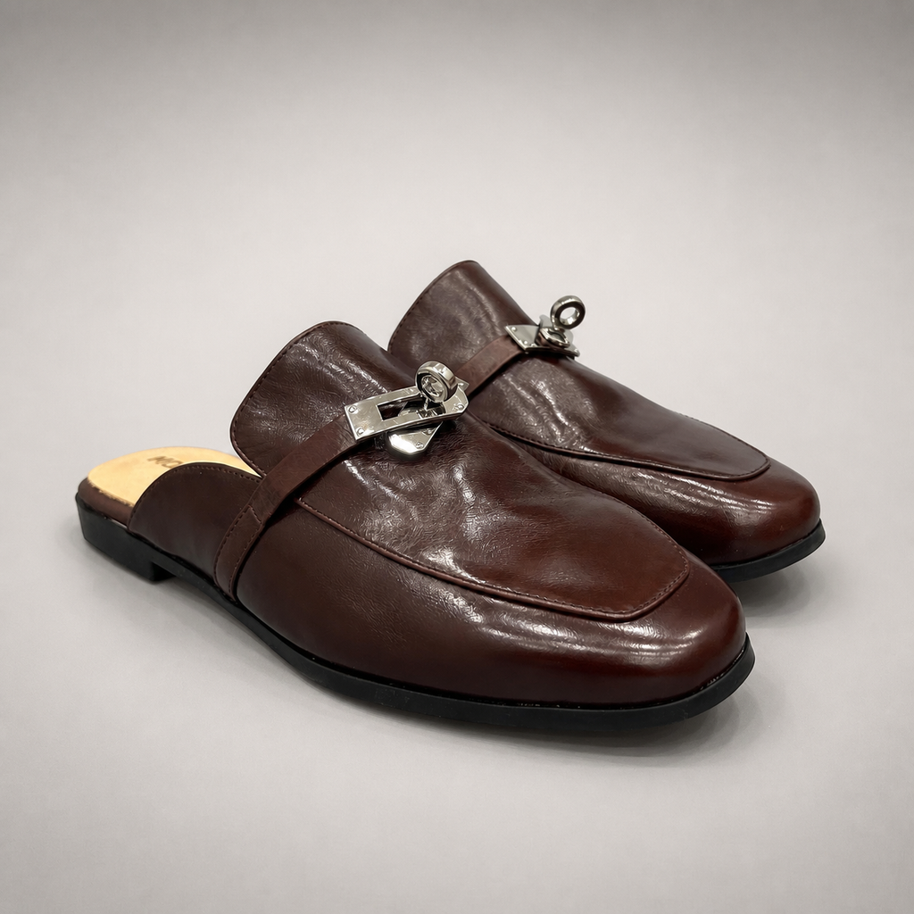 Brown mule loafer pair three-quarter view showing an open-back mule construction and metal vamp accent