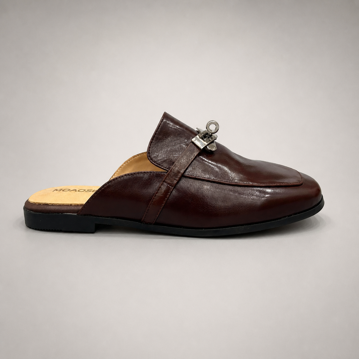 Brown mule loafer side profile showing an open-back mule construction and metal vamp accent