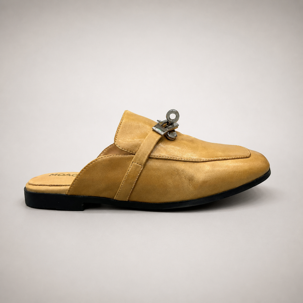 Tan mule loafer side profile showing an open-back mule construction and metal vamp accent