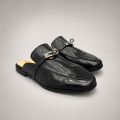 Black mule loafer pair three-quarter view showing an open-back mule construction and metal vamp accent
