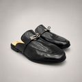 Black mule loafer pair three-quarter view showing an open-back mule construction and metal vamp accent
