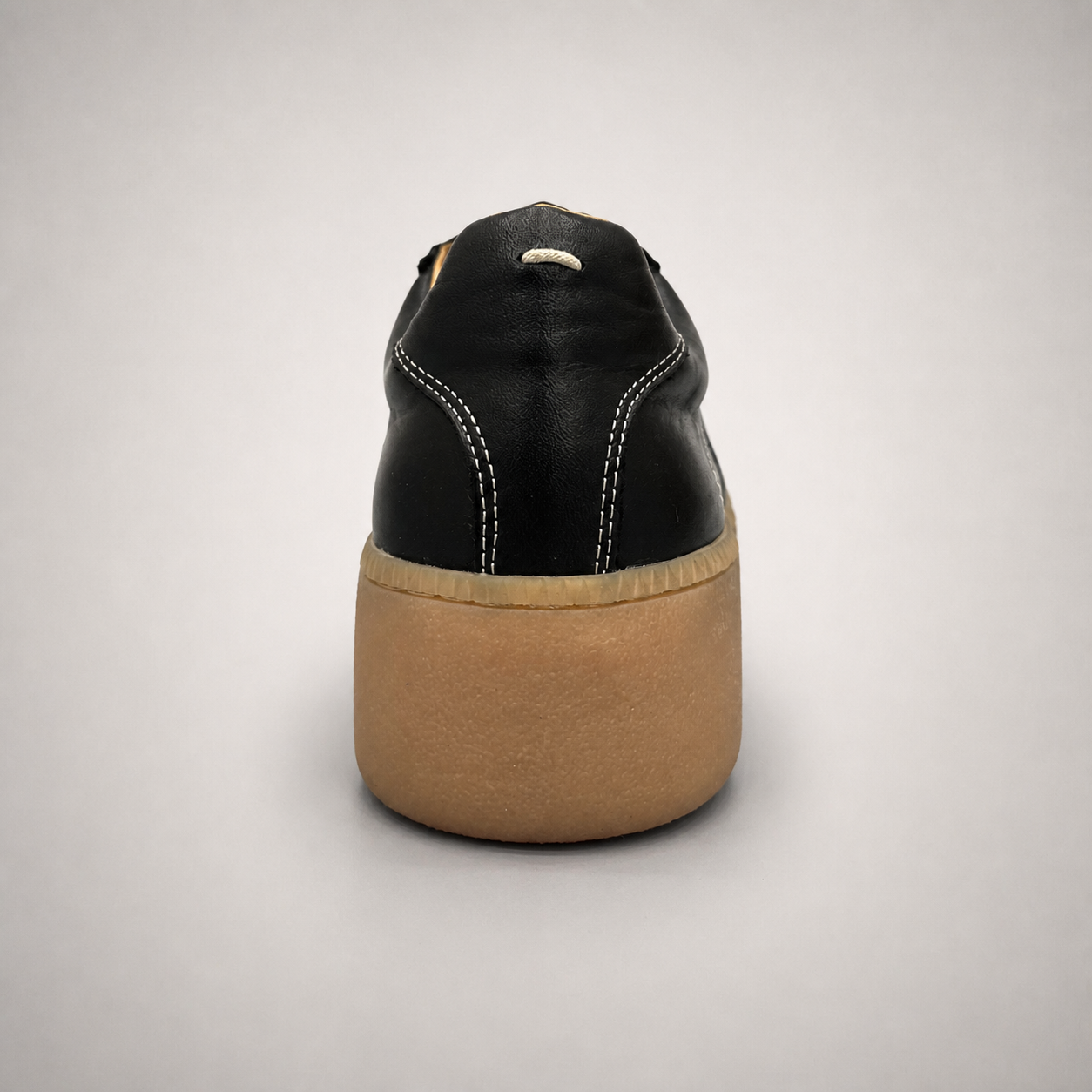 Black platform sneaker rear view showing a lace-up upper and raised platform sole