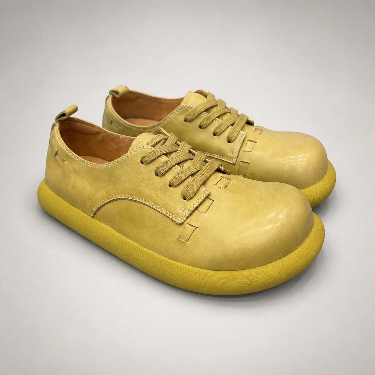 Yellow low-top sneaker pair three-quarter view showing a lace-up low-top construction