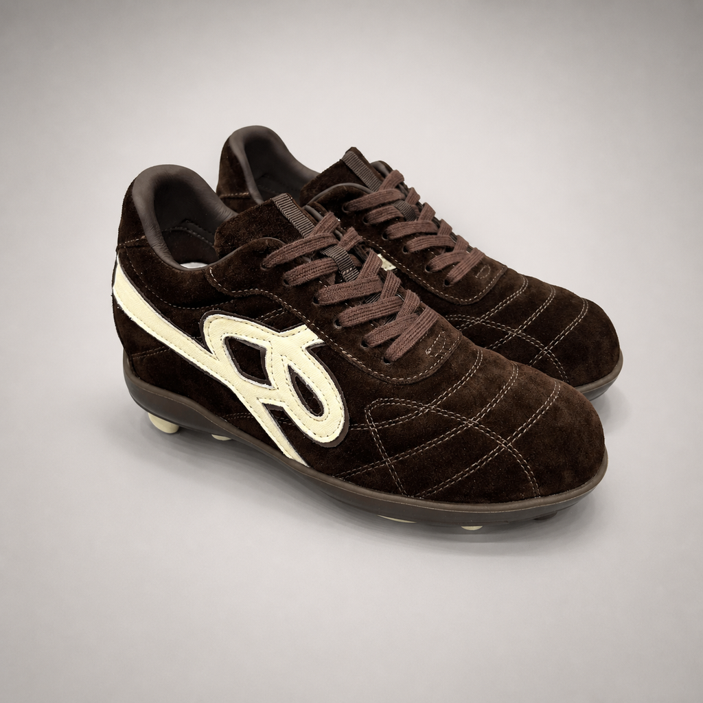 Dark Brown soccer shoe pair three-quarter view showing a lace-up upper and molded outsole studs