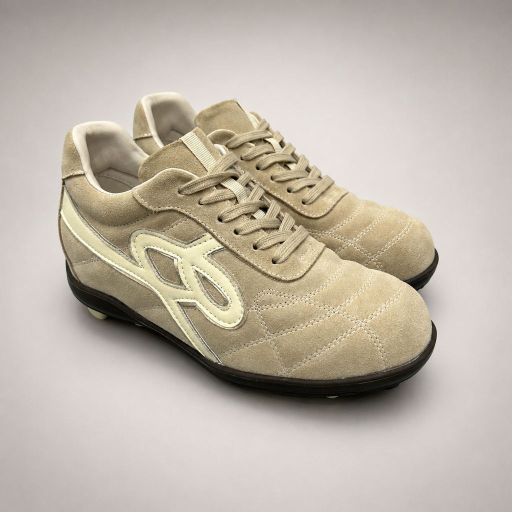 Beige soccer shoe pair three-quarter view showing a lace-up upper and molded outsole studs