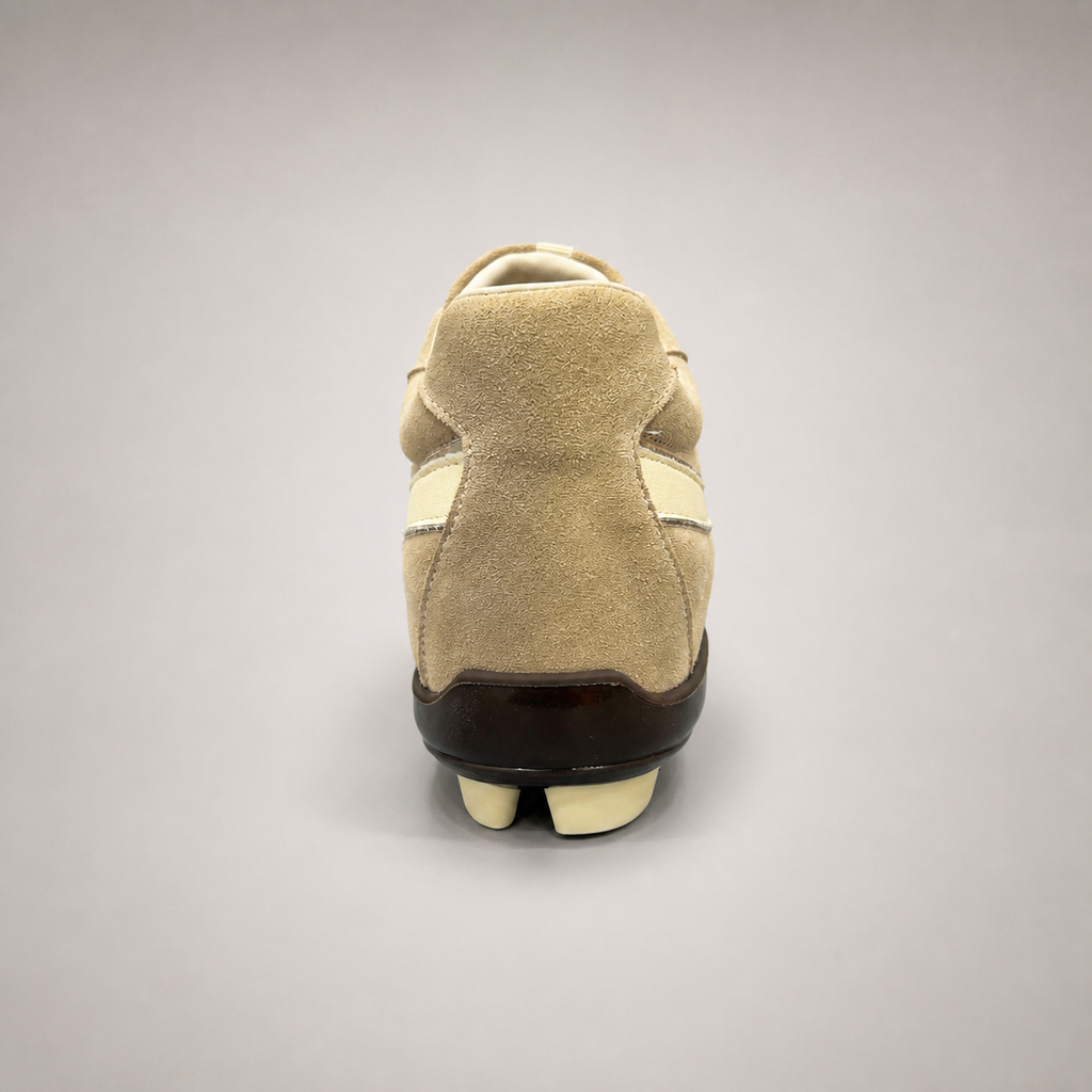 Beige soccer shoe rear view showing a lace-up upper and molded outsole studs