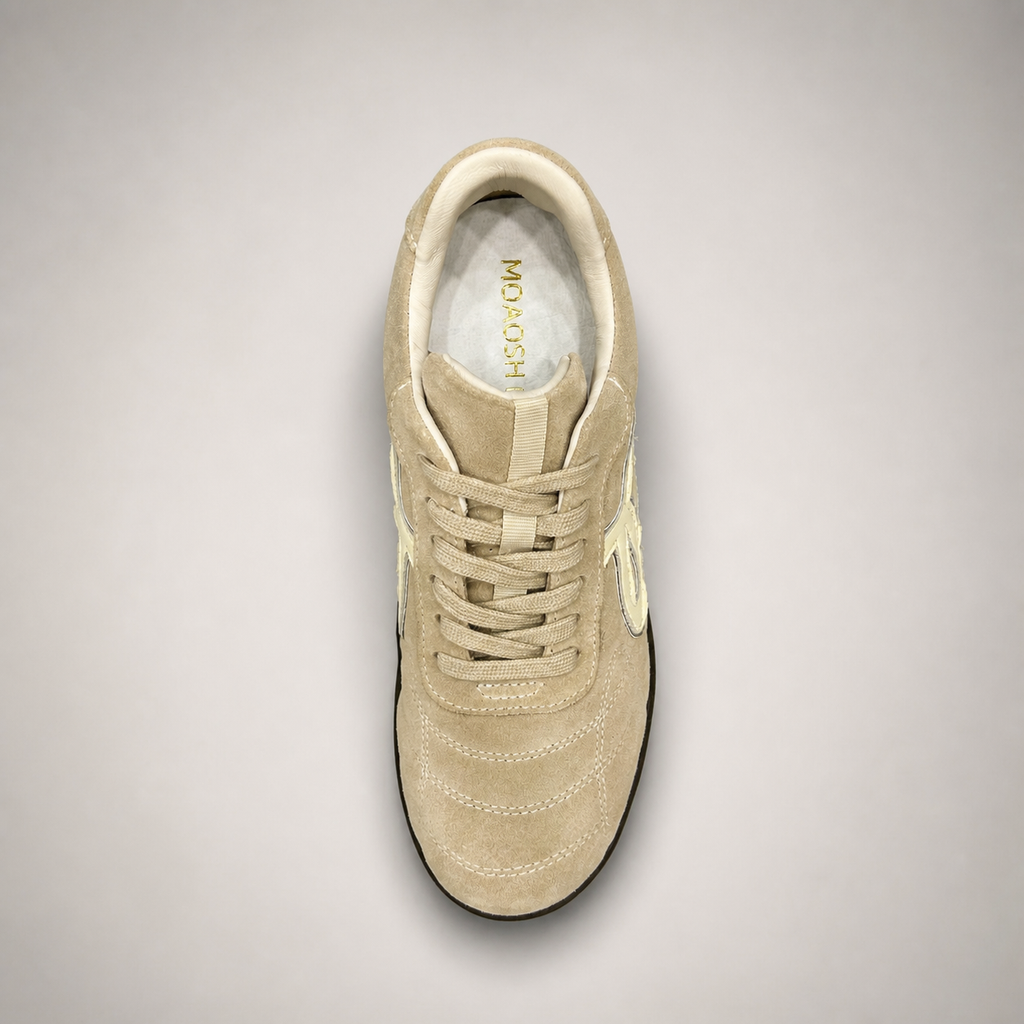 Beige soccer shoe top view showing a lace-up upper and molded outsole studs