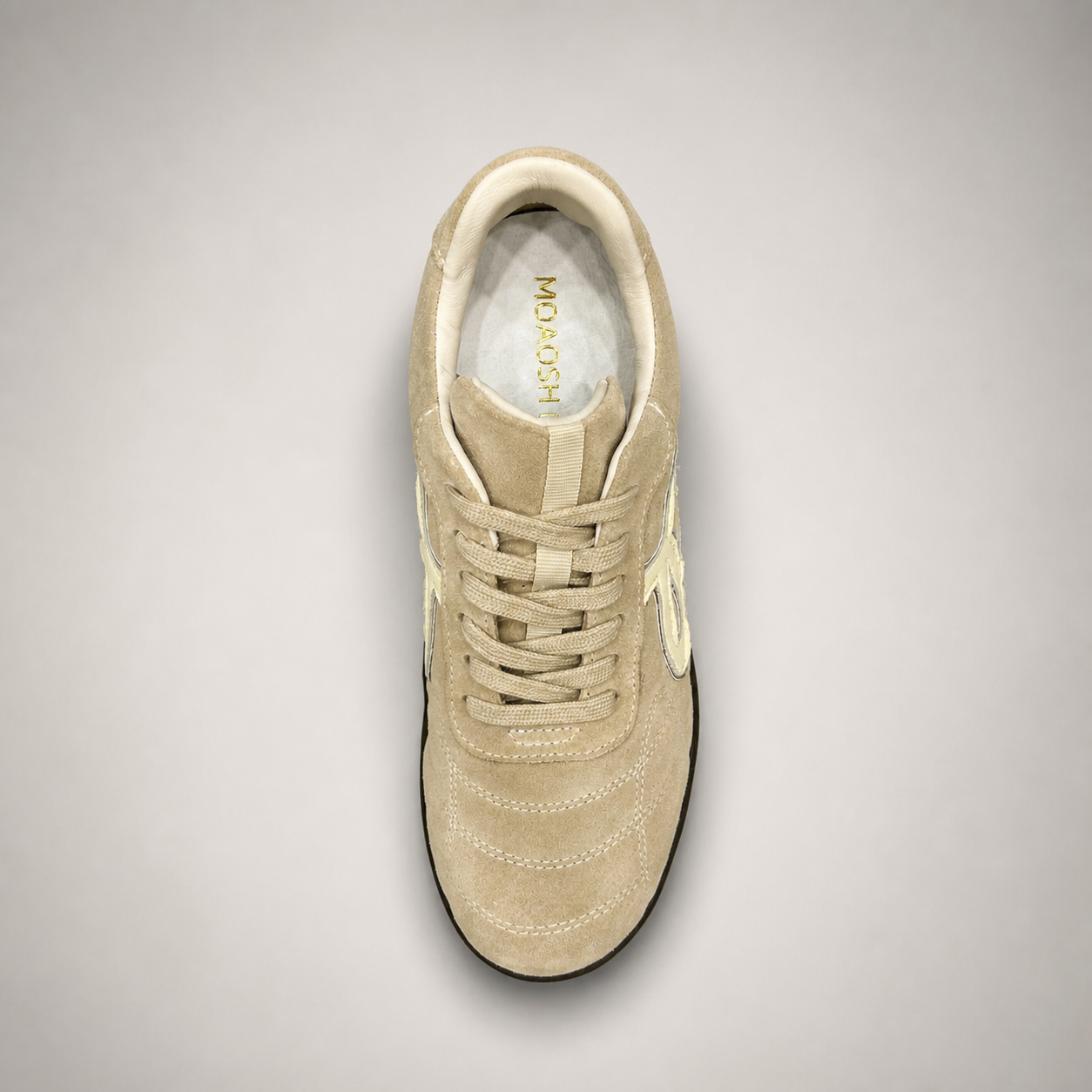 Beige soccer shoe top view showing a lace-up upper and molded outsole studs