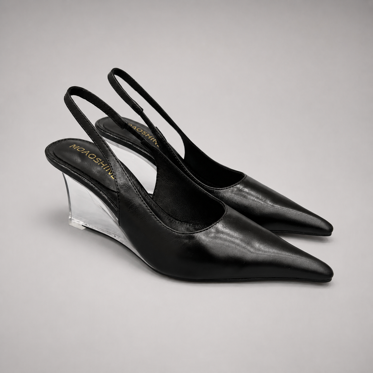 Black wedge slingback pump pair three-quarter view showing a pointed toe, slingback strap, and clear wedge heel
