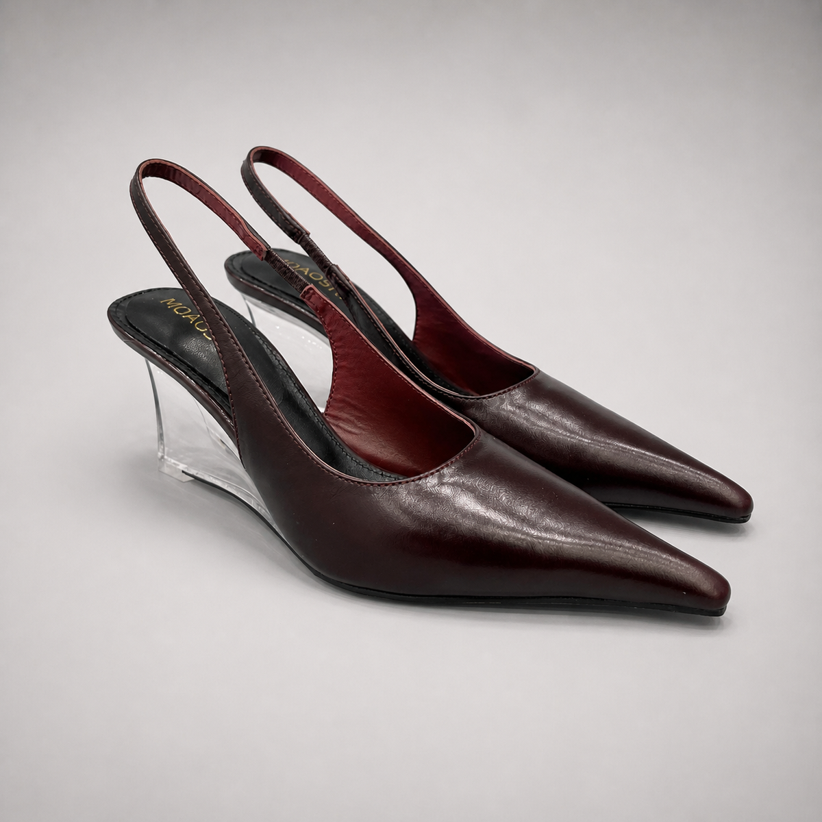 Burgundy wedge slingback pump pair three-quarter view showing a pointed toe, slingback strap, and clear wedge heel