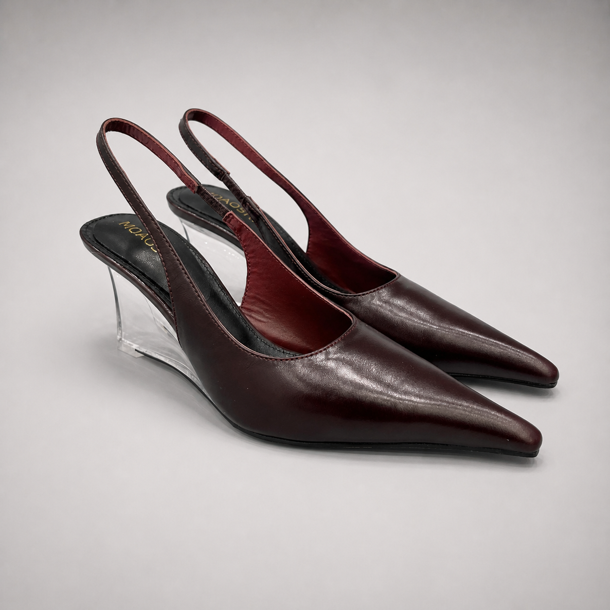 Burgundy wedge slingback pump pair three-quarter view showing a pointed toe, slingback strap, and clear wedge heel