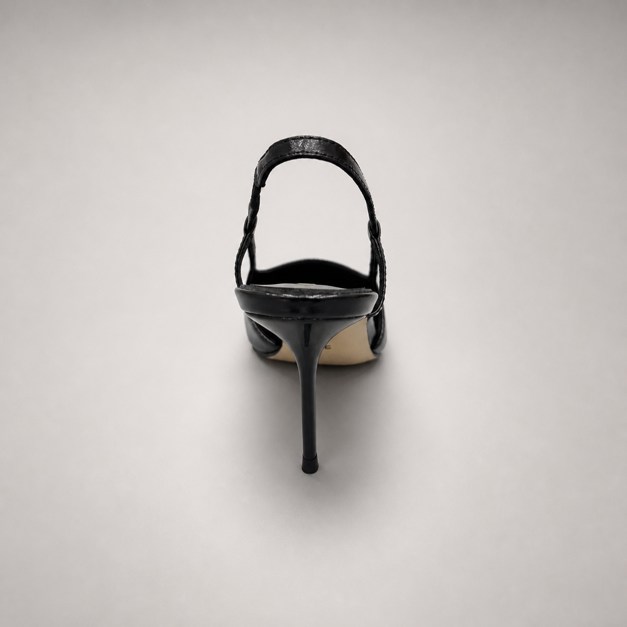 Black slingback pump rear view showing a pointed toe, slingback strap, and metal toe cap