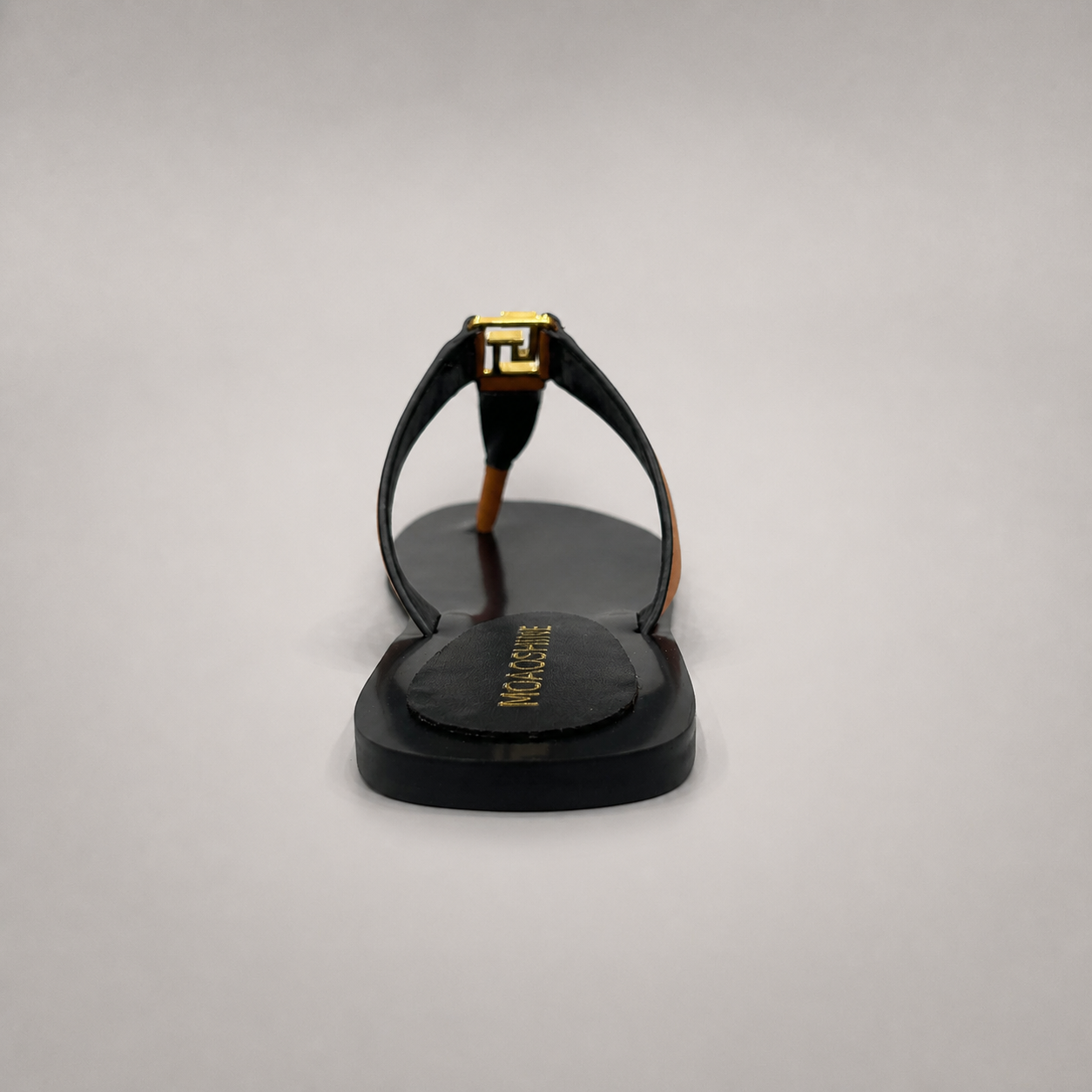 Brown flat sandal rear view showing a flat sole with a toe-loop strap