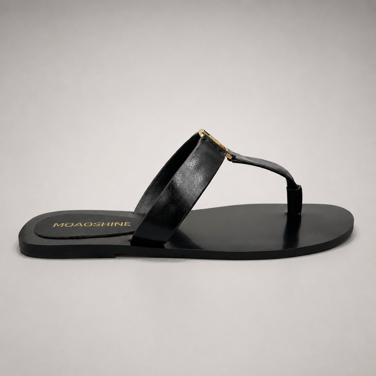Black flat sandal side profile showing a flat sole with a toe-loop strap