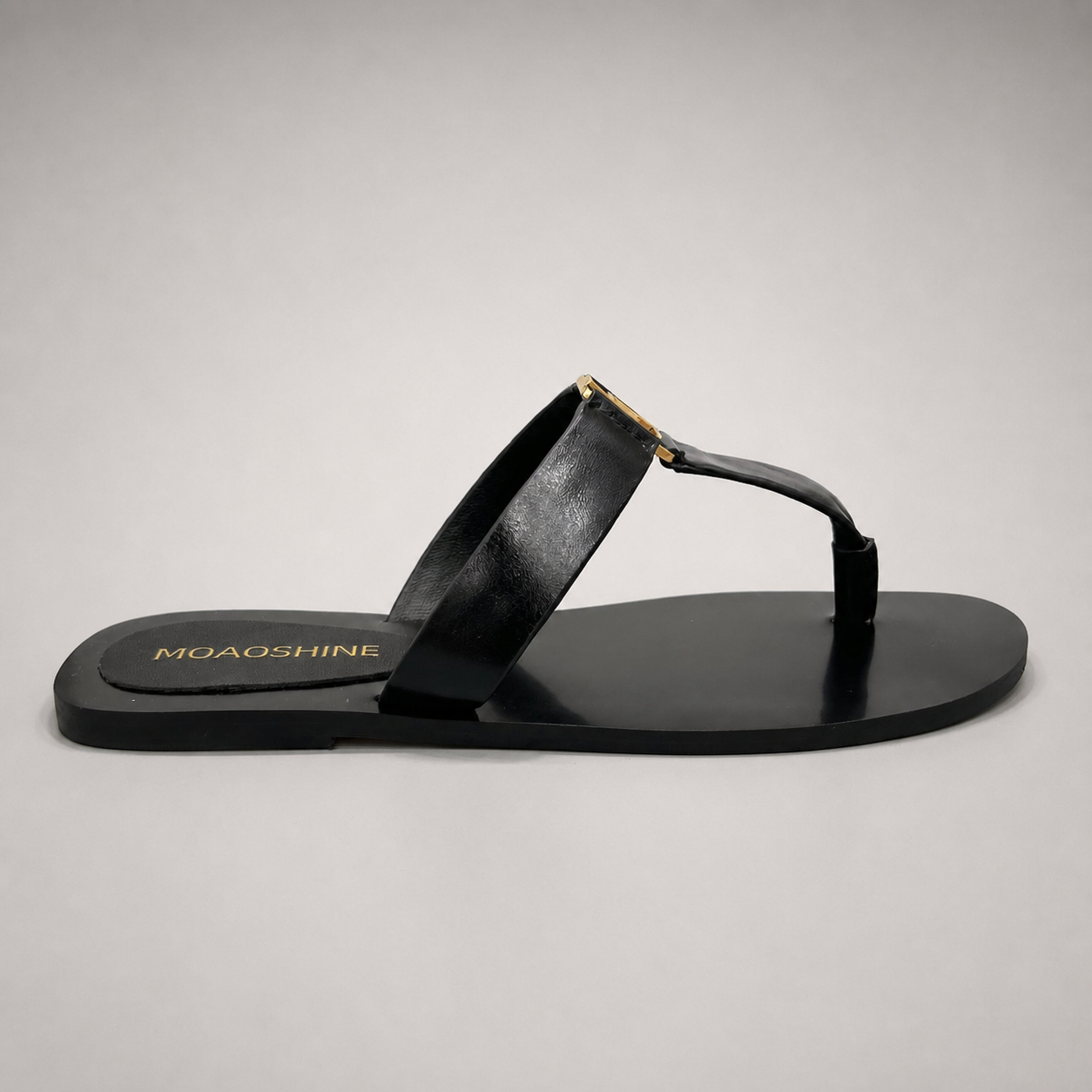 Black flat sandal side profile showing a flat sole with a toe-loop strap