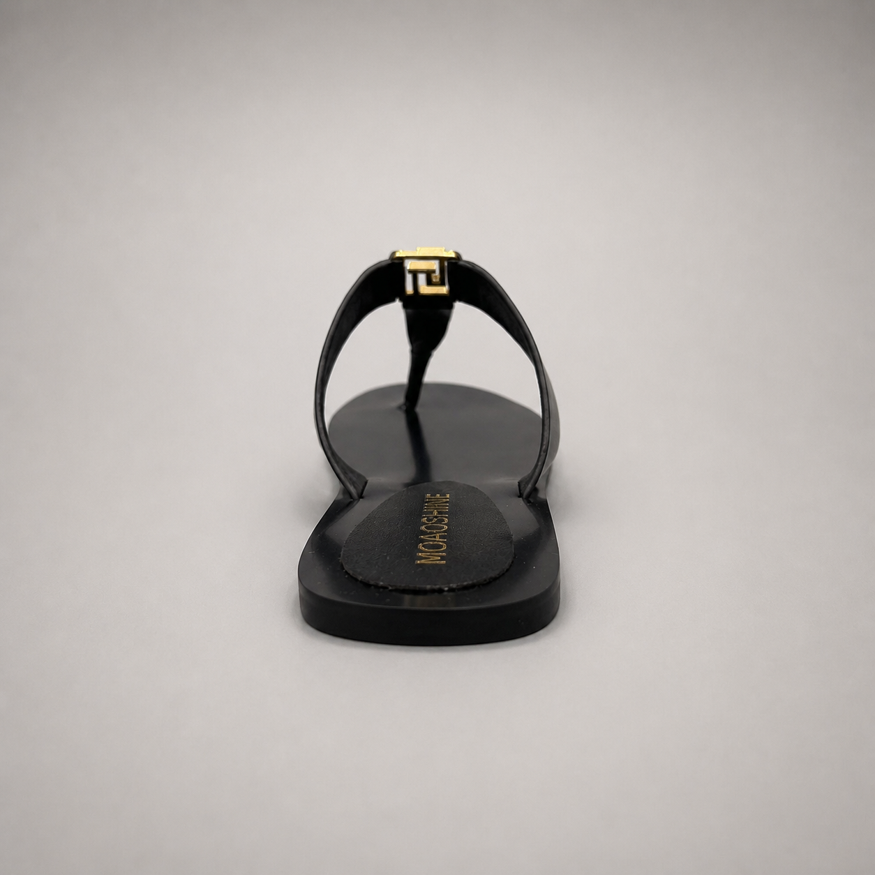 Black flat sandal rear view showing a flat sole with a toe-loop strap