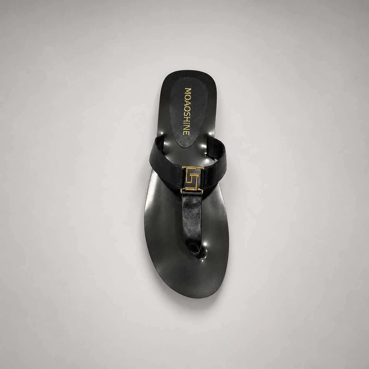 Black flat sandal top view showing a flat sole with a toe-loop strap