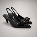 Black slingback pump pair three-quarter view showing a pointed toe and bow-shaped vamp ornament