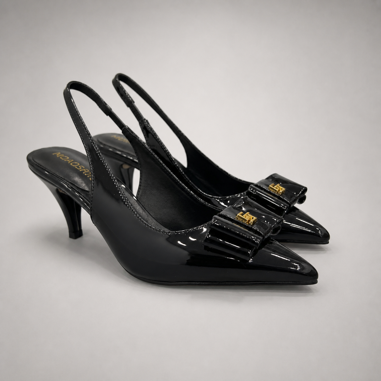 Black slingback pump pair three-quarter view showing a pointed toe and bow-shaped vamp ornament