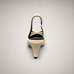 Ivory slingback pump rear view showing a pointed toe and bow-shaped vamp ornament