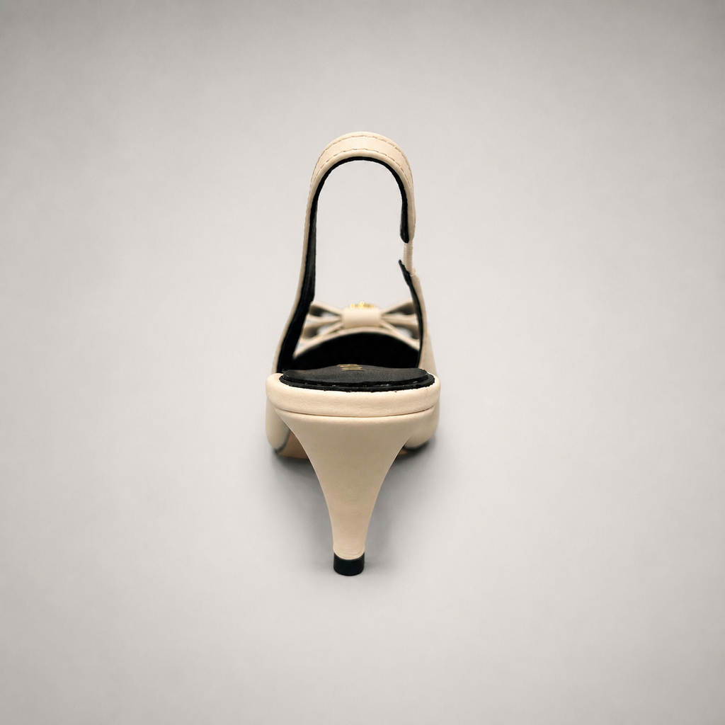 Ivory slingback pump rear view showing a pointed toe and bow-shaped vamp ornament