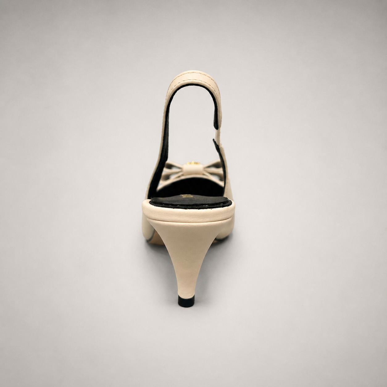 Ivory slingback pump rear view showing a pointed toe and bow-shaped vamp ornament