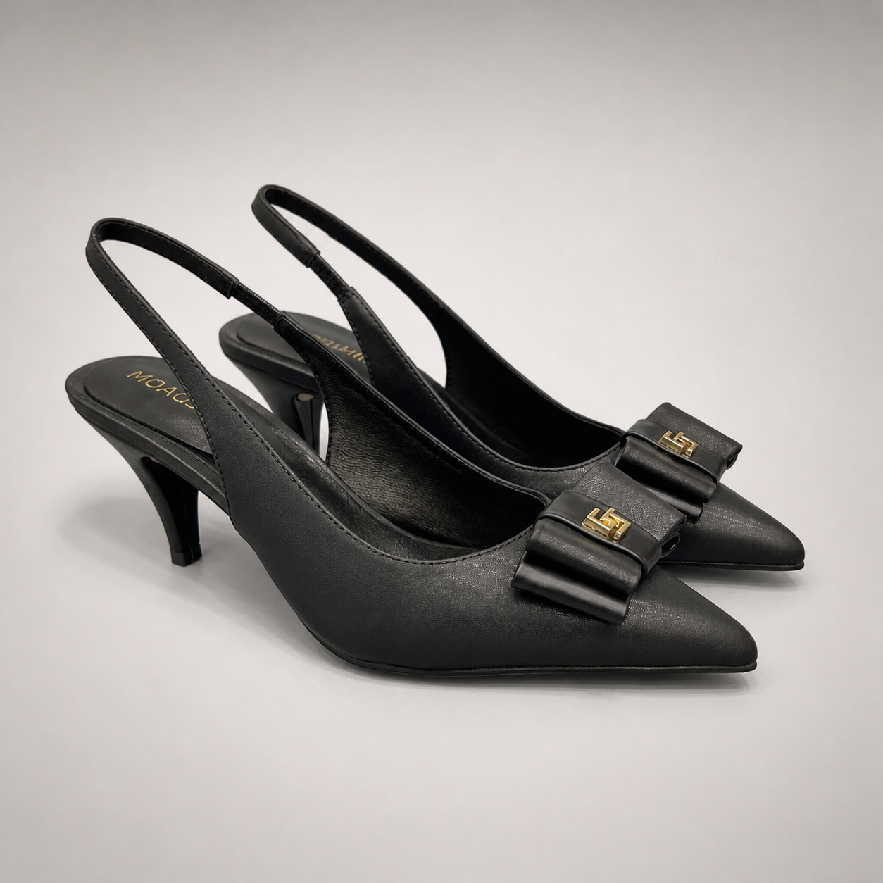 Black slingback pump pair three-quarter view showing a pointed toe and bow-shaped vamp ornament