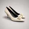 Ivory pump pair three-quarter view showing a pointed toe and bow-shaped vamp ornament