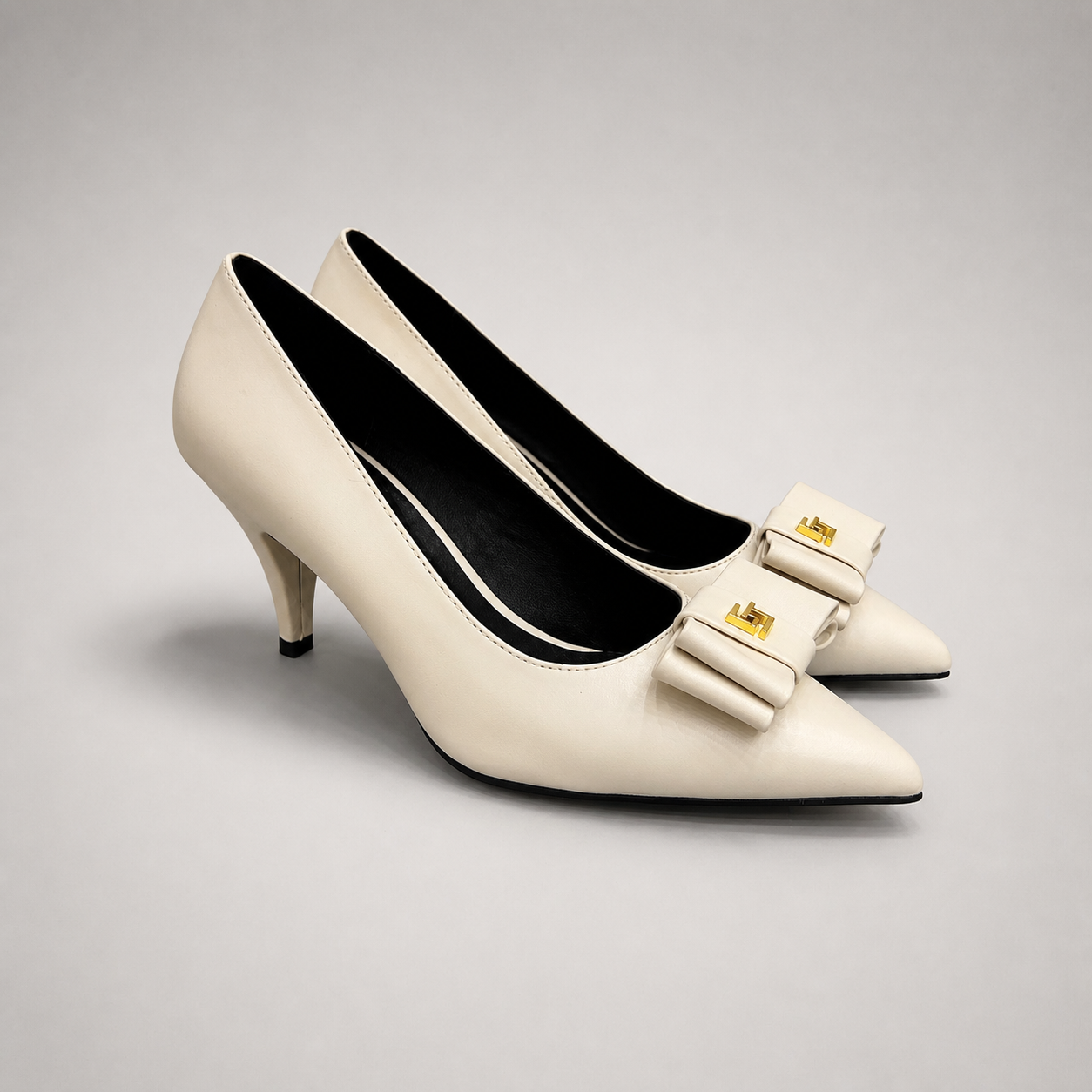 Ivory pump pair three-quarter view showing a pointed toe and bow-shaped vamp ornament