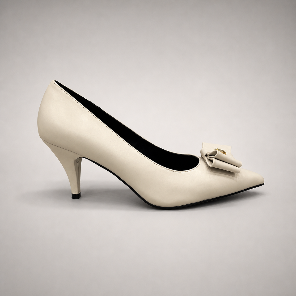 Ivory pump side profile showing a pointed toe and bow-shaped vamp ornament