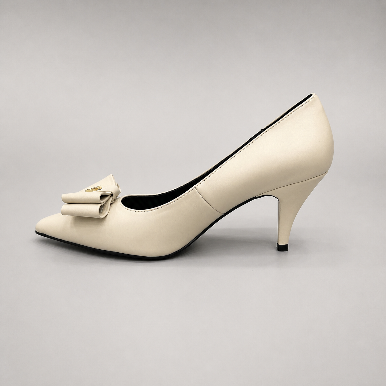 Ivory pump opposite side profile showing a pointed toe and bow-shaped vamp ornament